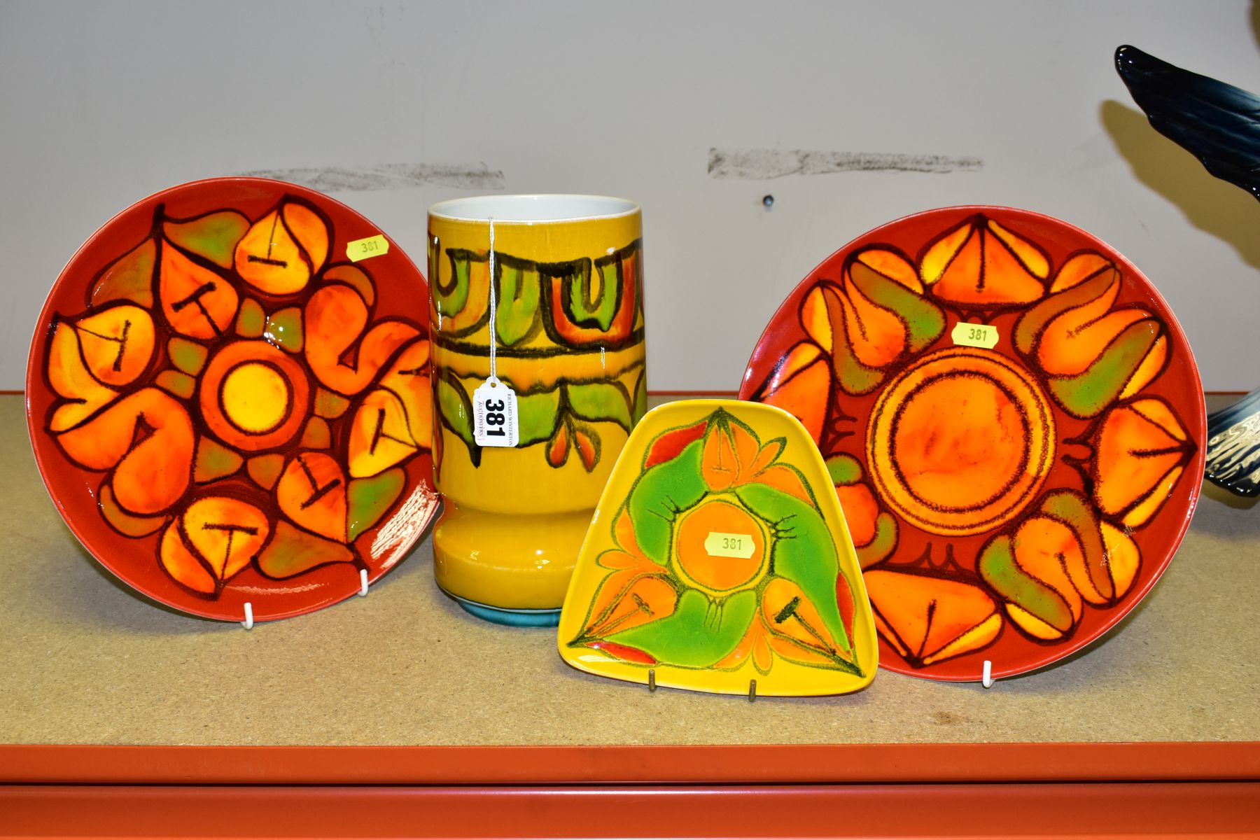 FOUR PIECES OF POOLE POTTERY, abstract designs, comprising two red ground plates, both 25.5cm