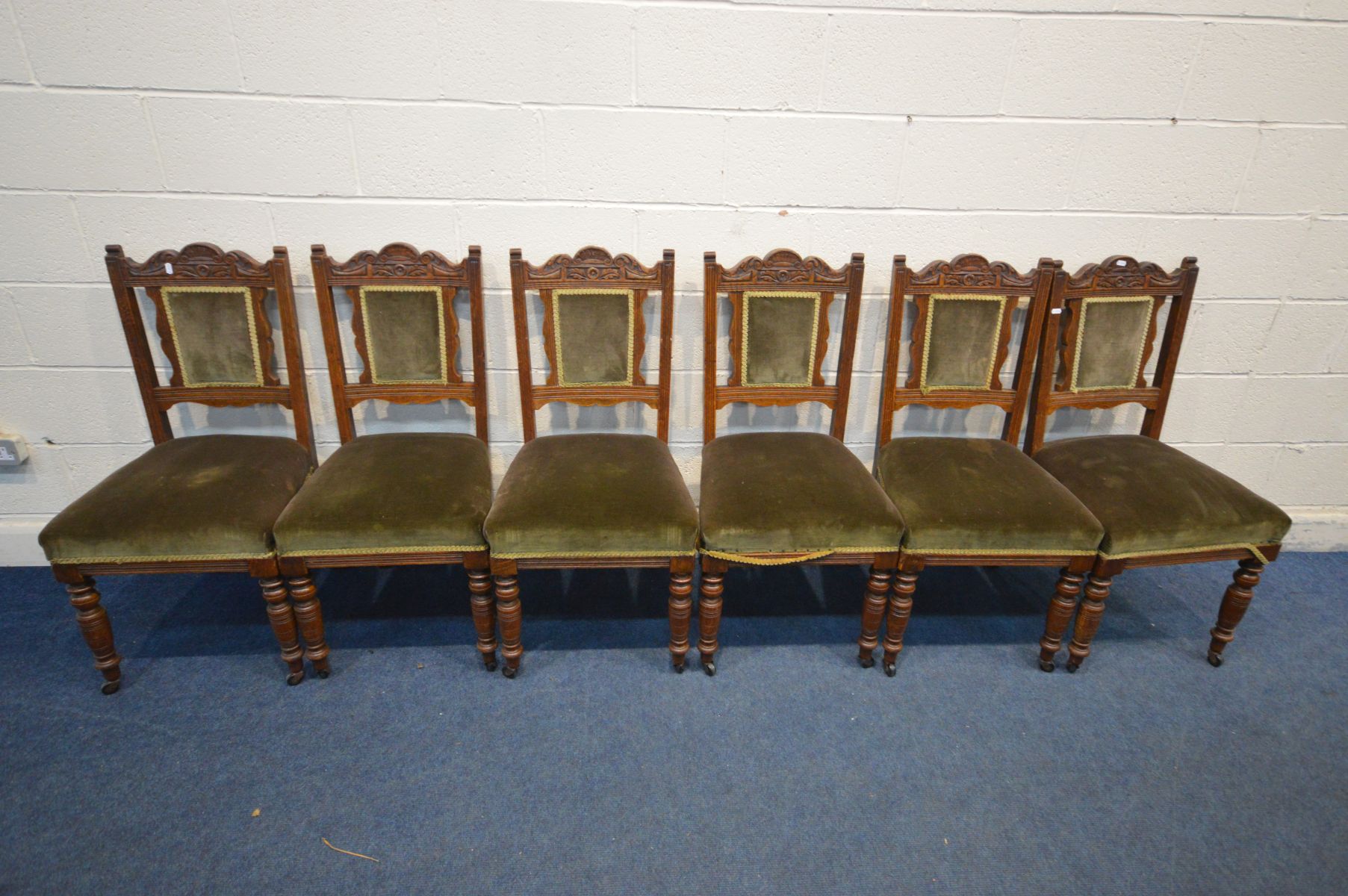 A SET OF SIX EDWARDIAN DINING CHAIRS with dark green upholstery on ceramic casters