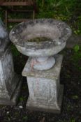 A WEATHERED COMPOSITE GARDEN URN, on a separate plinth, diameter 50cm x height 80cm x height of base