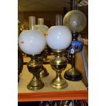 FOUR BRASS BASED TWIN BURNER OIL LAMPS, one with a blue glass hand painted reservoir, the column