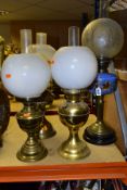 FOUR BRASS BASED TWIN BURNER OIL LAMPS, one with a blue glass hand painted reservoir, the column