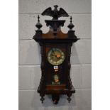 AN WALNUT VIENNA WALL CLOCK, with central eagle finial, enclosing a 5ins dial, height 80cm (