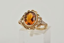 A 9CT GOLD CITRINE AND DIAMOND RING, centring on a collet mounted oval cut citrine, openwork scallop