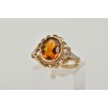 A 9CT GOLD CITRINE AND DIAMOND RING, centring on a collet mounted oval cut citrine, openwork scallop