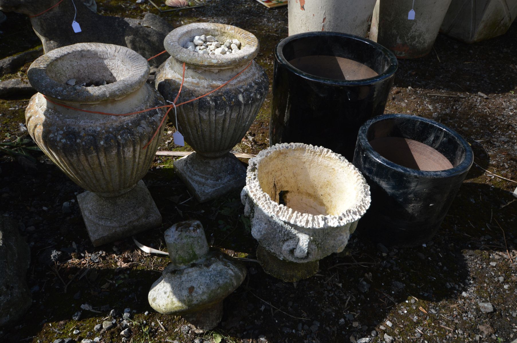 A PAIR OF COMPOSITE URNS, height 42cm, along with two black glazed graduated plant pots, a small urn