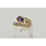 A YELLOW METAL AMETHYST AND SEED PEARL RING, of a cross over design, set with a single oval cut