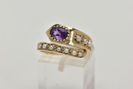 A YELLOW METAL AMETHYST AND SEED PEARL RING, of a cross over design, set with a single oval cut