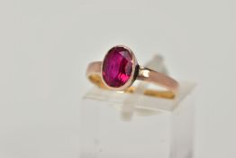 A VICTORIAN YELLOW METAL RING, collet mounted oval cut synthetic ruby, plain polished band, rubbed