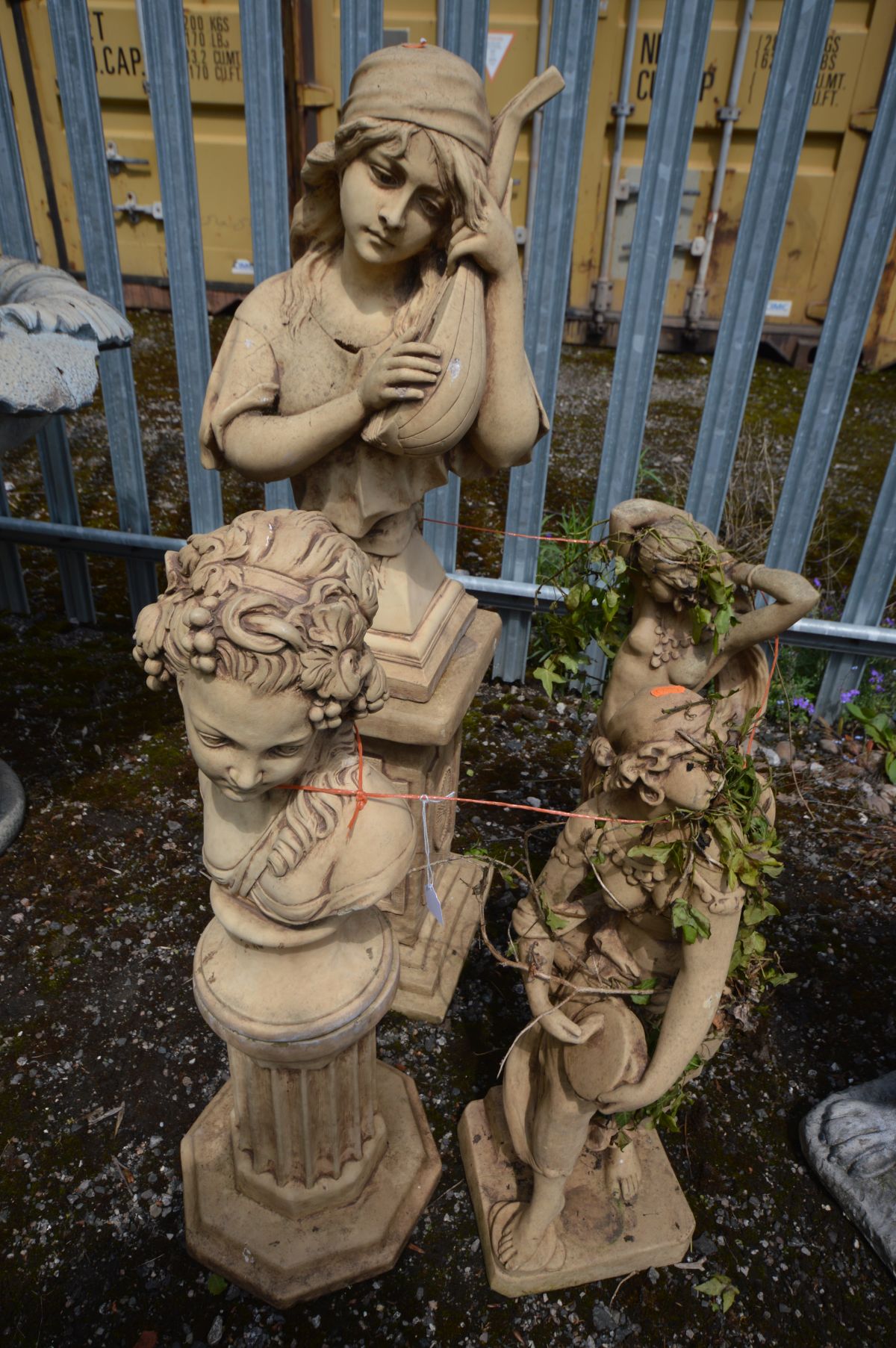 FOUR SIMILAR COMPOSITE GARDEN FIGURES, to include a female playing a mandolin, on a separate plinth,