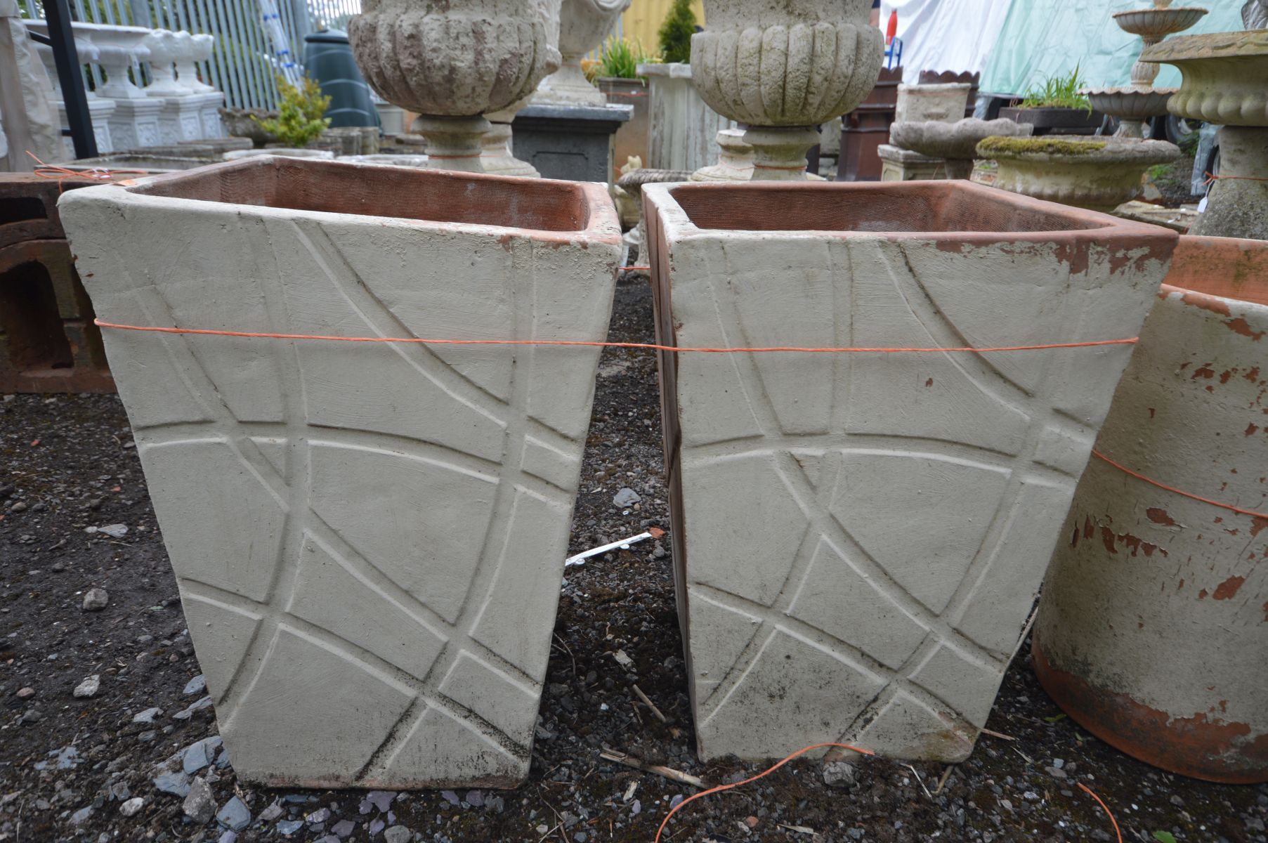 A PAIR OF TAPERED SQUARE TERRACOTTA PLANTERS with a modern carved decoration, outer side later