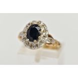 A 9CT GOLD SAPPHIRE AND DIAMOND CLUSTER RING, raised cluster, centring on an oval cut blue sapphire,