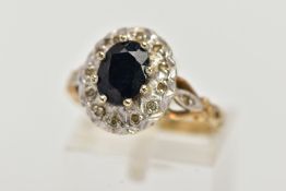 A 9CT GOLD SAPPHIRE AND DIAMOND CLUSTER RING, raised cluster, centring on an oval cut blue sapphire,