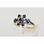 A YELLOW METAL SAPPHIRE AND DIAMOND CLUSTER RING, set with a central claw set, circular cut blue