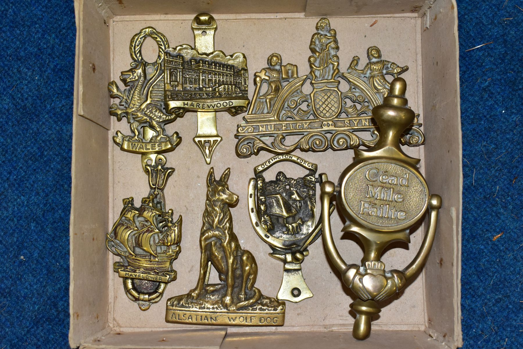 A SMALL BOX OF VARIOUS BRASS DOOR KNOCKERS, to include 'Cead Mile Failte', height 20cm, 'mayflower',