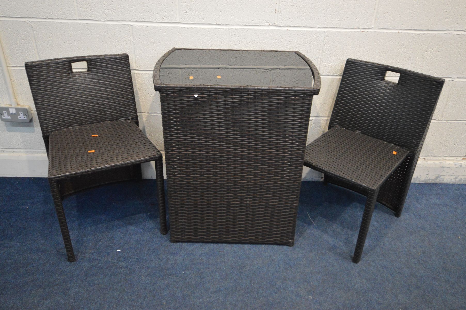 A BLACK GLASS TOP RATTAN EFFECT PATIO TABLE enclosing two chairs (3)