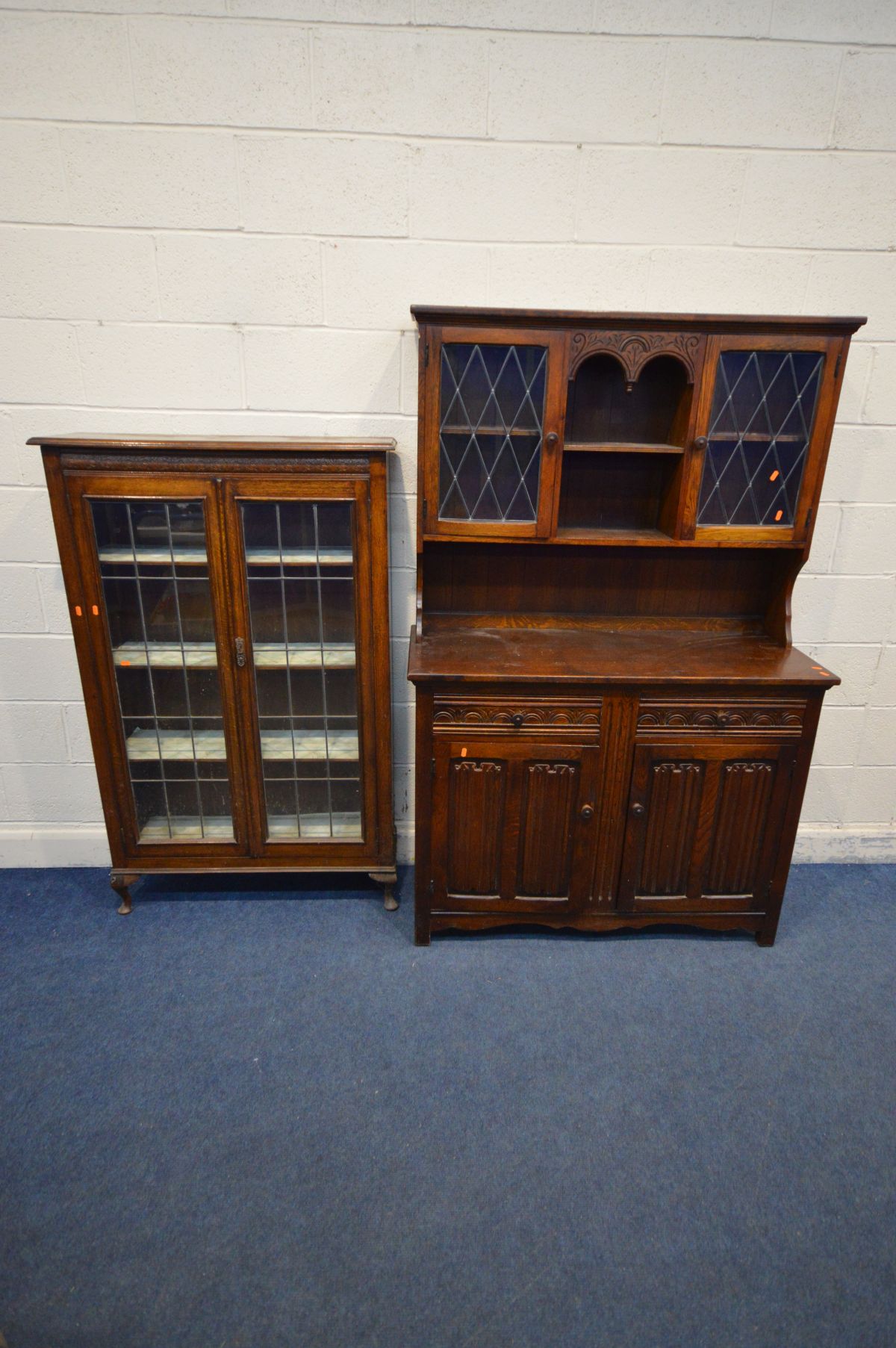 AN EARLY 20TH OAK LEAD GLAZED BOOKCASE, the double doors enclosing three adjustable shelves, on