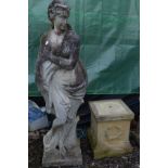 A LARGE WEATHERED COMPOSITE GARDEN STATUE of a semi clad lady in flowing robes, collecting the