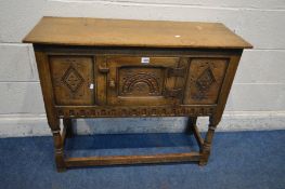 A REPRODUCTION OAK CREDENCE CABINET, single carved panel door flanked by two other carved panels