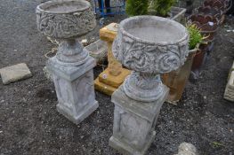 A PAIR OF COMPOSITE GARDEN PLANTERS with acanthus leaf detail, on a tall matched plinth, diameter