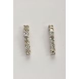 A PAIR OF WHITE METAL DIAMOND DROP EARRINGS, each designed as a wavy line drop set with seven claw