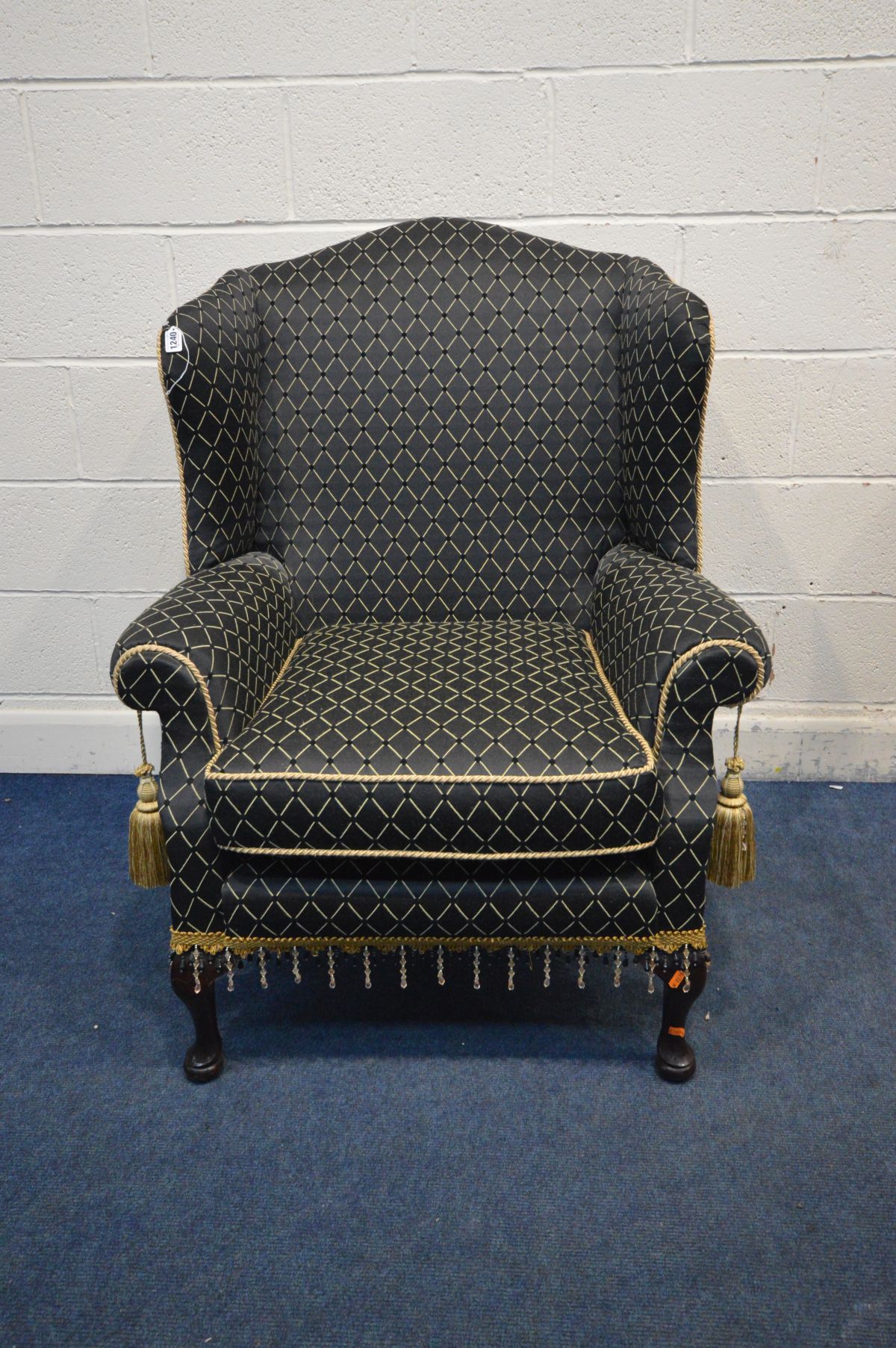 A GEORGIAN STYLE WINGBACK ARMCHAIR, with black ground and patterned upholstery, width 80cm x inner