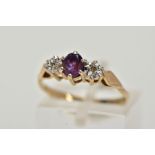 A 9CT GOLD THREE STONE RING, centring on a claw set, oval cut amethyst, flanked with illusion set