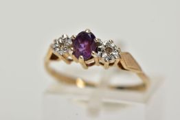 A 9CT GOLD THREE STONE RING, centring on a claw set, oval cut amethyst, flanked with illusion set