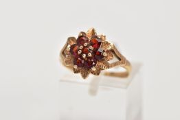 A 9CT GOLD GARNET CLUSTER RING, the raised cluster in the form of a flower, set with seven