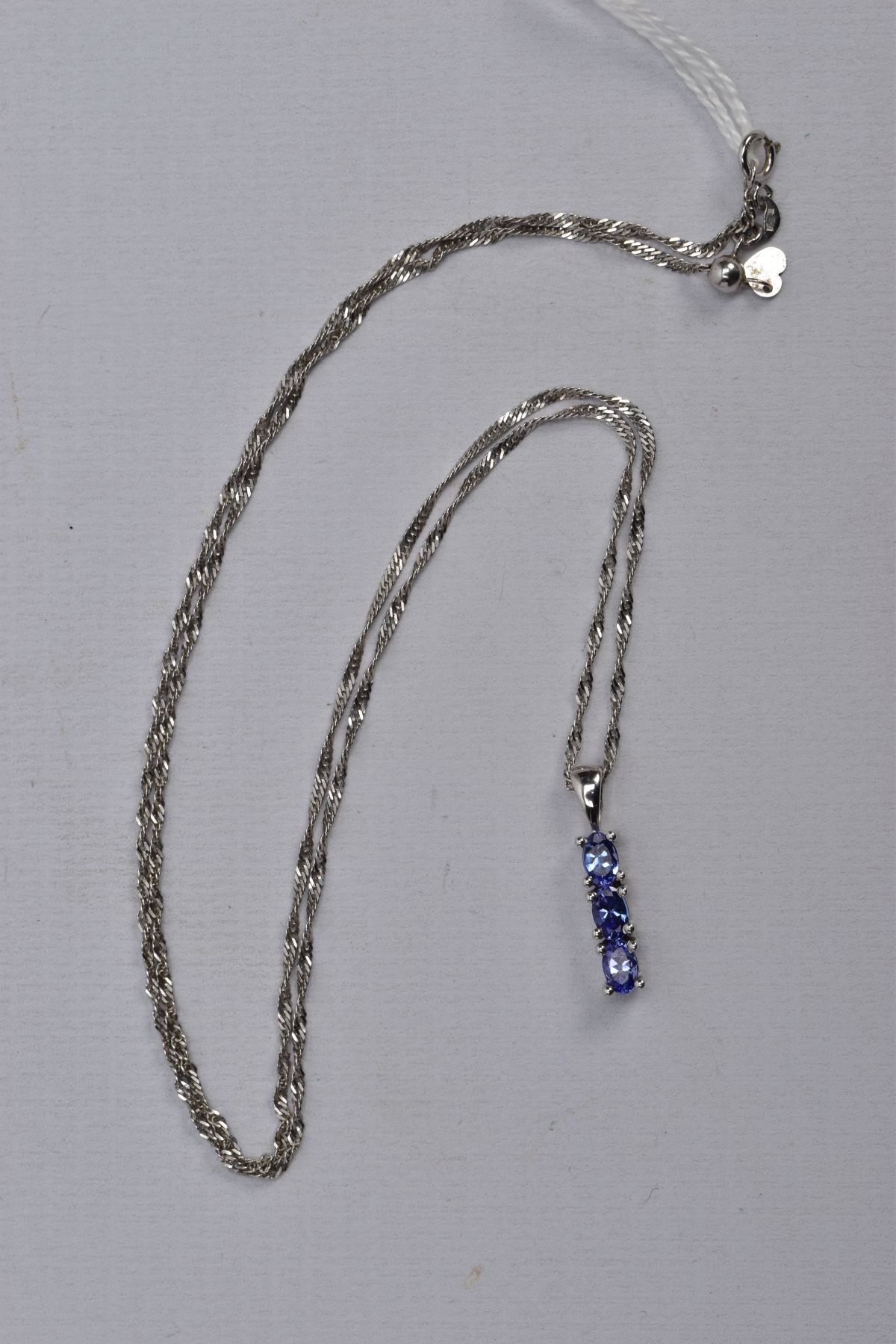 A 9CT WHITE GOLD, TANZANITE PENDANT NECKLACE, the pendant designed with a row of three claw set, - Image 2 of 3