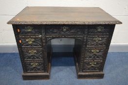 A 19TH CENTURY FOLIATE CARVED OAK KNEEHOLE DESK, with nine assorted drawers, later brass handles,