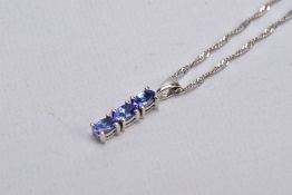 A 9CT WHITE GOLD, TANZANITE PENDANT NECKLACE, the pendant designed with a row of three claw set,