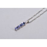 A 9CT WHITE GOLD, TANZANITE PENDANT NECKLACE, the pendant designed with a row of three claw set,