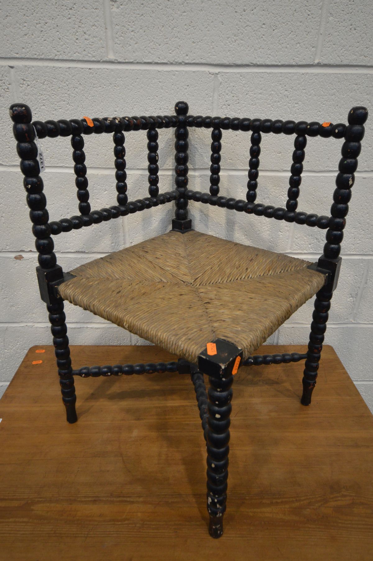 AN ARTS AND CRAFTS EBONISED BOBBIN TURNED CORNER CHAIR, with a rush seat (over painted)