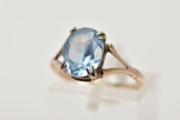 A YELLOW METAL, BLUE TOPAZ DRESS RING, designed with a double four claw set, oval cut blue topaz,