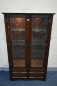 A JAYCEE OAK TWO DOOR LEAD GLAZED DISPLAY CABINET, with four drawers, and internal lighting, width