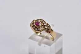 A YELLOW METAL RUBY AND DIAMOND CLUSTER RING, centring on an oval cut ruby, within a single cut