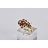 A YELLOW METAL RUBY AND DIAMOND CLUSTER RING, centring on an oval cut ruby, within a single cut