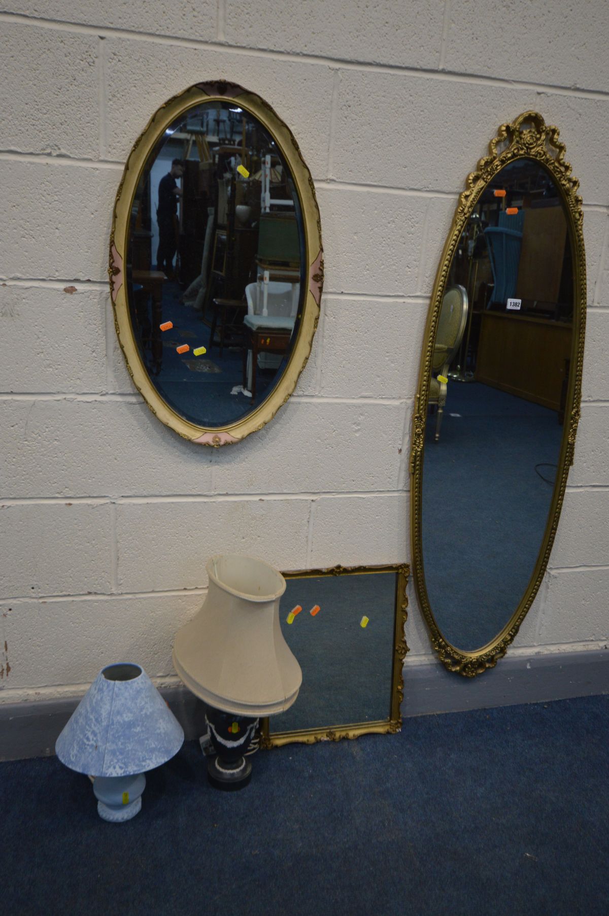 AN OVAL FOLIATE GILT WOOD WALL MIRROR, another gilt mirror and another mirror, along with two