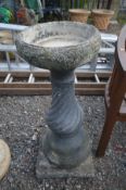 A COMPOSITE CIRCULAR BIRD BATH, on a separate twisted base, diameter 35cm x height 85cm