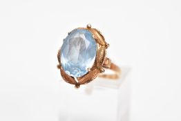 A 9CT GOLD AQUAMARINE RING, designed with a claw set, oval cut aquamarine, within a textured swag