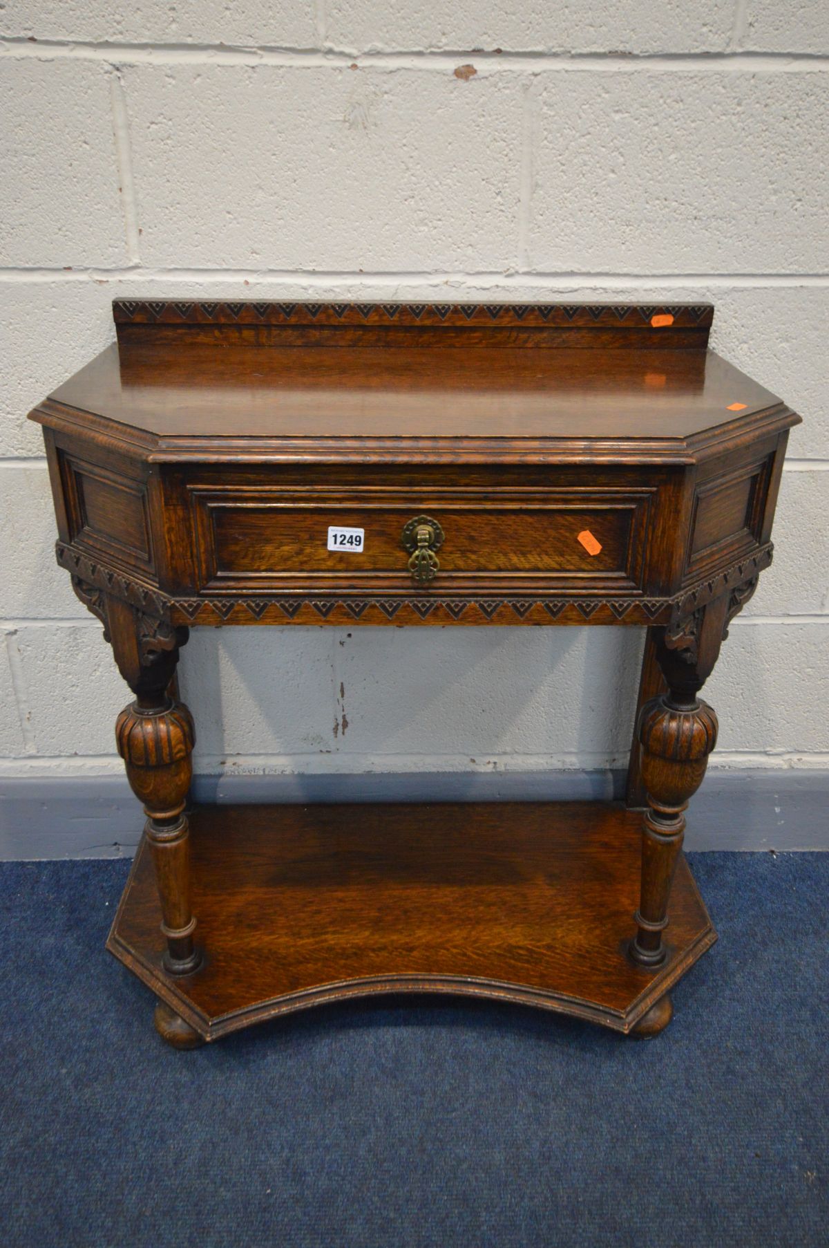 AN OAK SIDE TABLE with a raised back, canted front corners and a single frieze drawer, on acorn