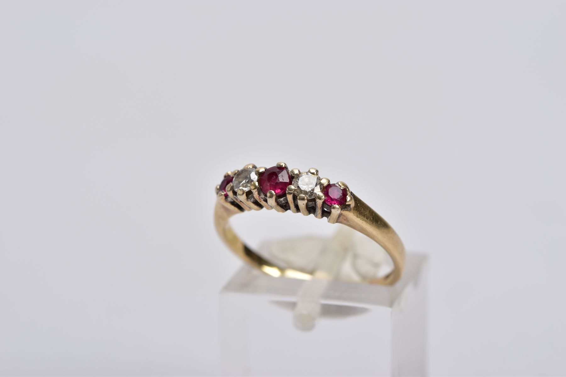 A 9CT GOLD RUBY AND DIAMOND RING, designed with three graduated circular cut rubies, interspaced