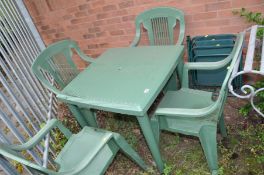 A GREEN PLASTIC GARDEN TABLE 78cm wide and deep 74cm high, four matching chairs and two folding