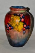 A WILLIAM MOORCROFT POTTERY FLAMBE BALUSTER VASE IN THE LEAF AND BERRIES PATTERN, painted and