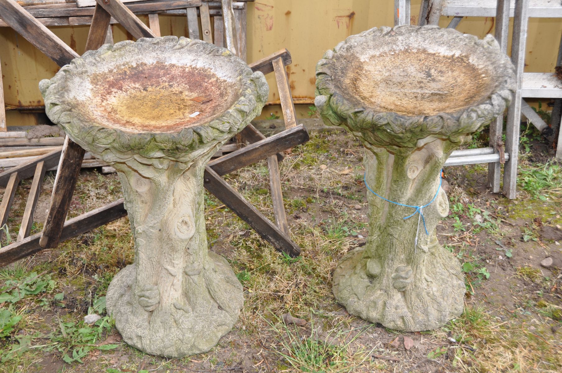 A PAIR OF COMPOSITE ONE PIECE BIRD BATHS in the form of a tree trunk with foliate bowl and birds