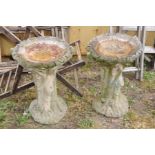 A PAIR OF COMPOSITE ONE PIECE BIRD BATHS in the form of a tree trunk with foliate bowl and birds