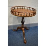 A REPRODUCTION MAHOGANY OCCASIONAL TABLE, with a spindled gallery, to a tripod base, on ball and