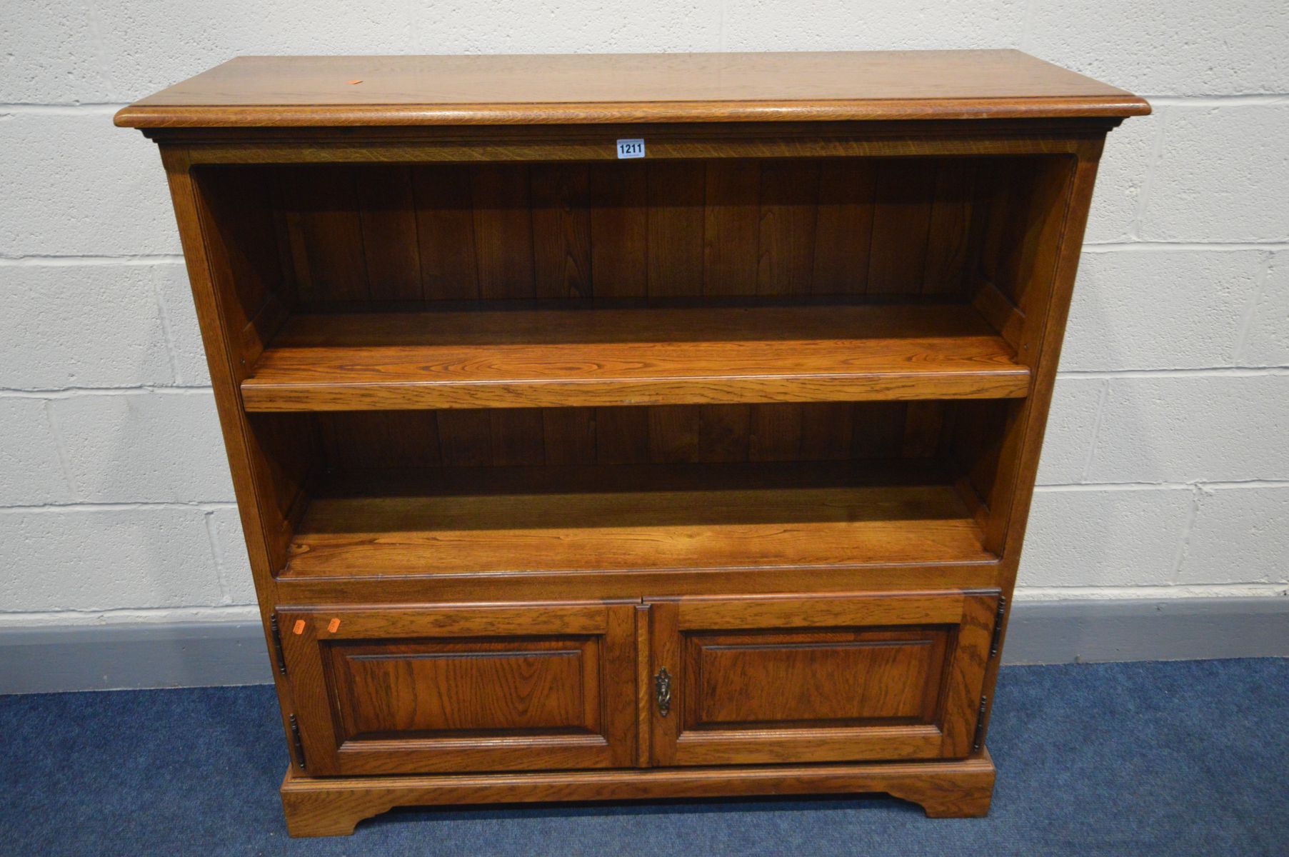 A REPRODUCTION OAK OPEN BOOKCASE, with fielded panels to the sides, single adjustable shelf, above