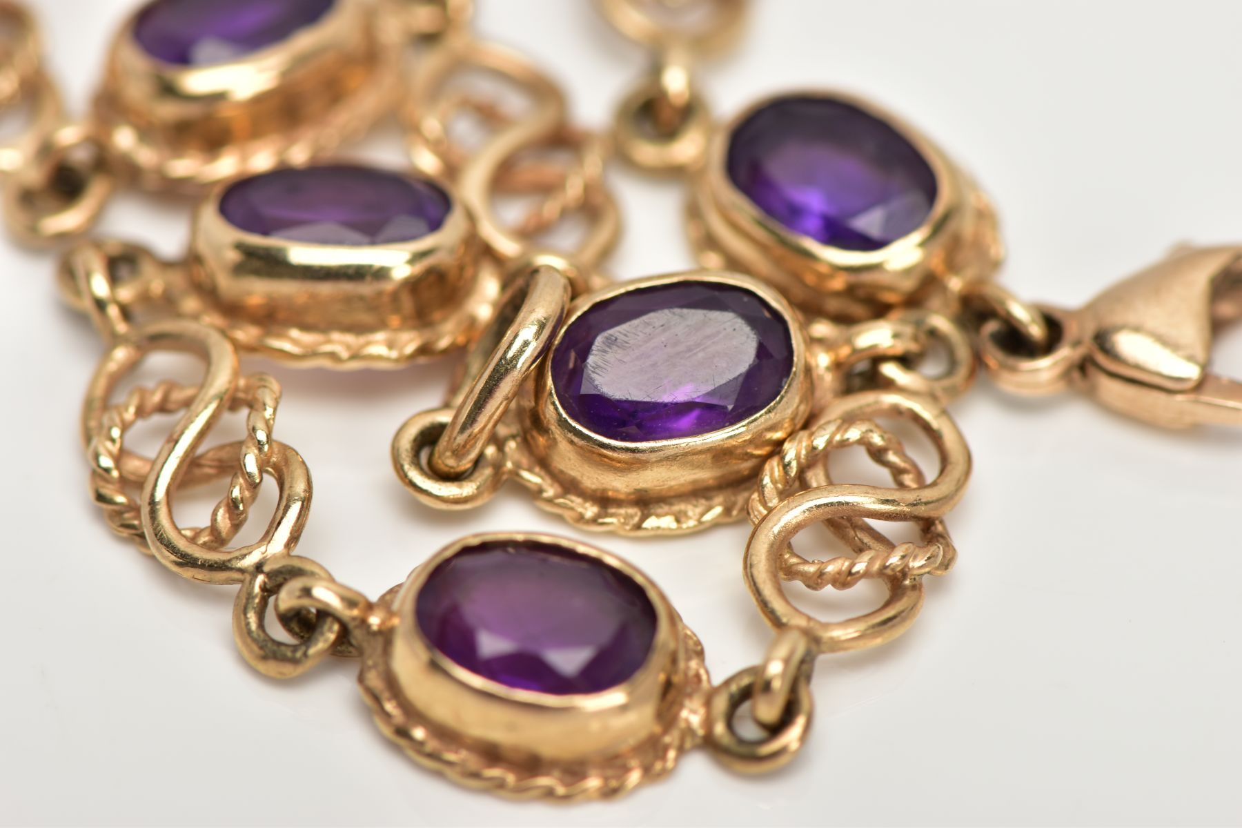 A 9CT GOLD AMETHYST LINE BRACELET, designed with seven oval cut amethysts, each with a collet - Image 4 of 4
