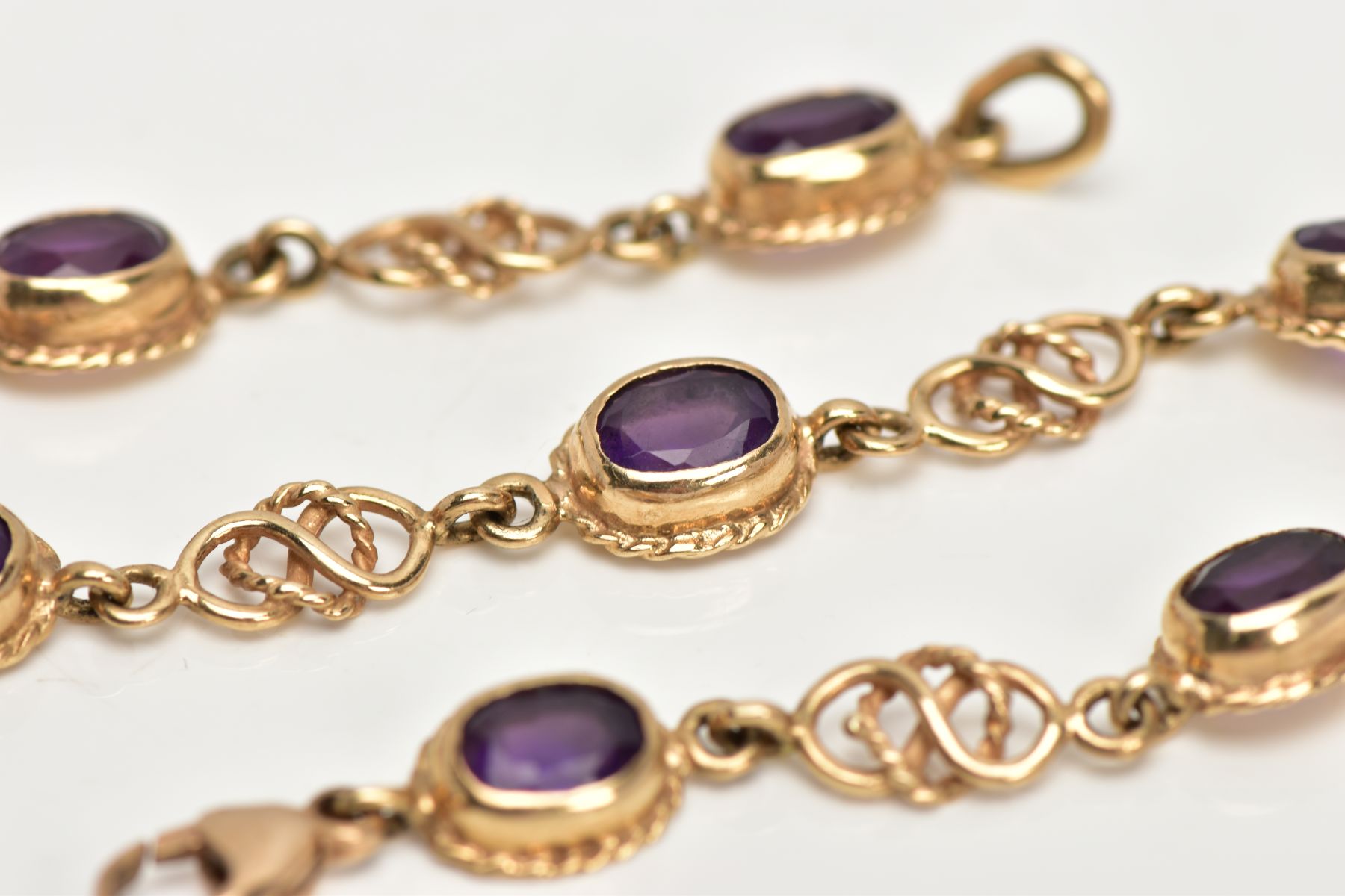 A 9CT GOLD AMETHYST LINE BRACELET, designed with seven oval cut amethysts, each with a collet - Image 2 of 4